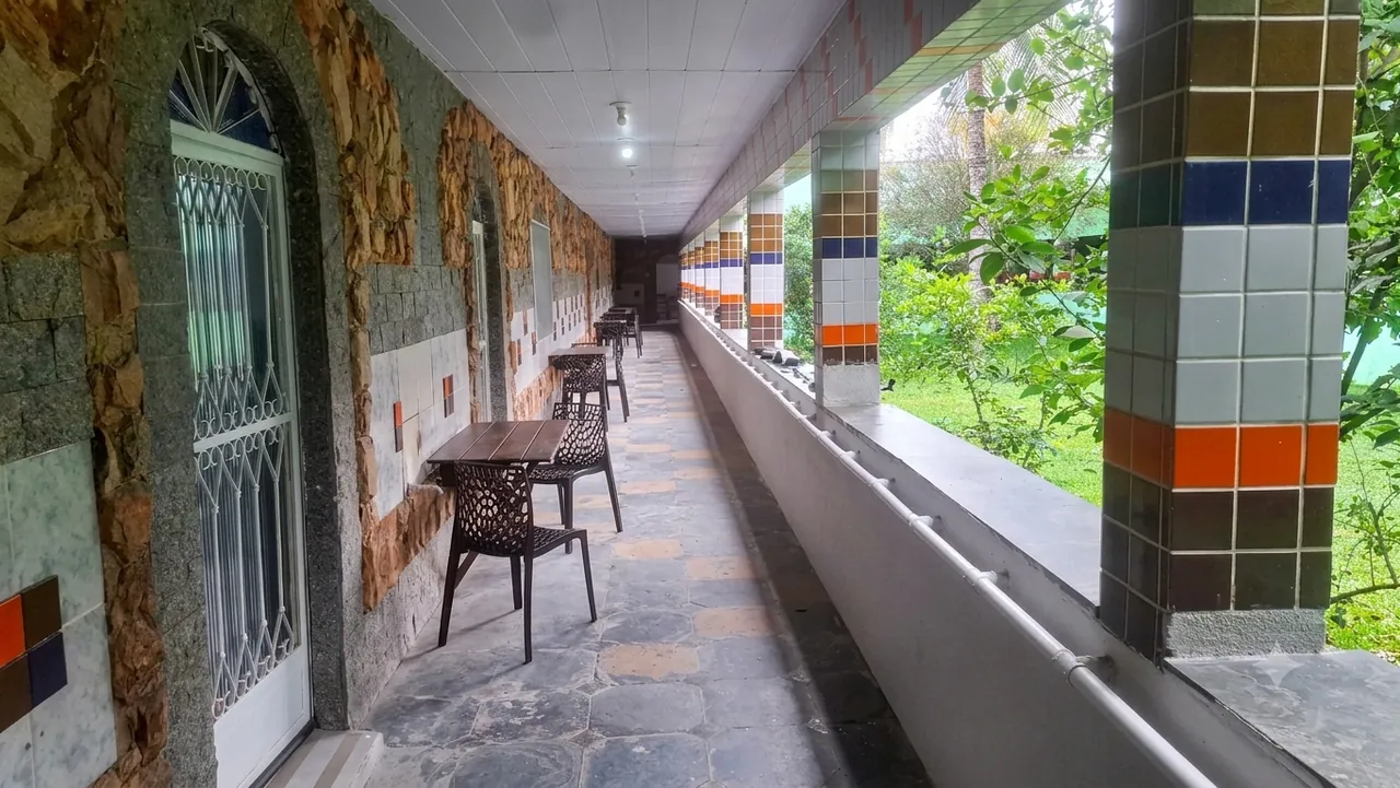 Varanda coberta com área de descanso e vista para o jardim